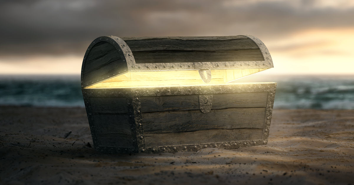 A partially opened treasure chest on a beach emits a gold light